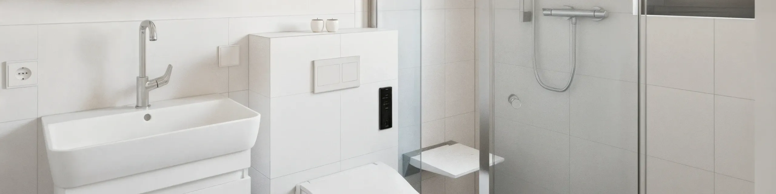 Kleines, modernes Badezimmer mit wandhängendem WC, eckigem Waschbecken und Glasdusche. Die Ausstattung ist platzsparend und funktional gestaltet. Alle Elemente sind in Weiß und Edelstahl gehalten.