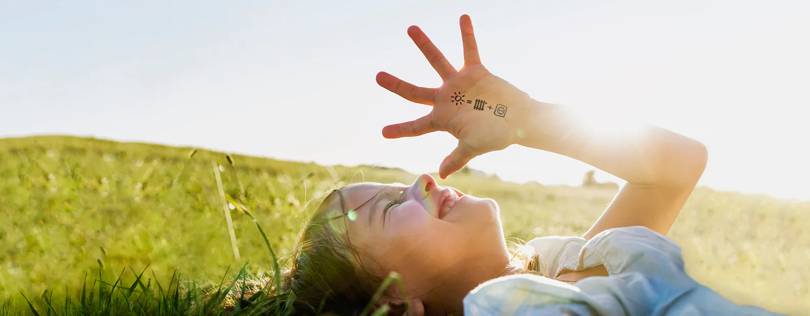 Kind mit Wärme und Strom Symbolen auf der Hand auf grüner Wiese.