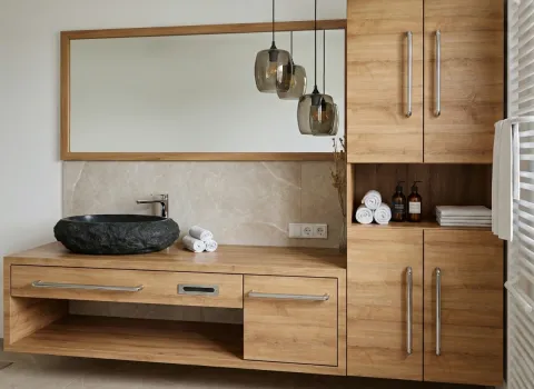 Stilvoller Waschtisch mit Holzfronten, Naturstein-Schale und integriertem Stauraum im minimalistischen Bad.
