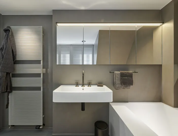 Ein stilvolles Badezimmer mit schlichten Formen, einem beleuchteten Spiegelschrank und einem klaren, minimalistischen Design.