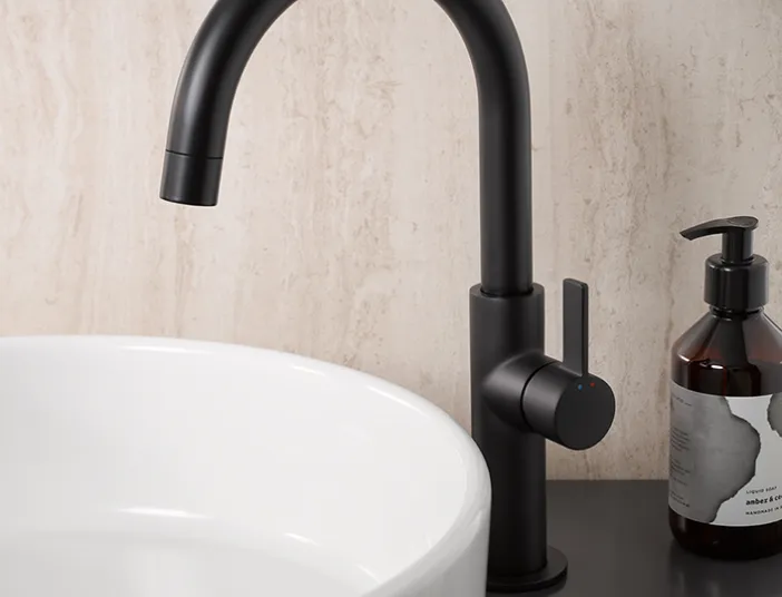 AquaXPro Slim Plus Waschtischarmatur in Schwarz matt neben einem weißen Aufsatzwaschbecken im modernen Badezimmer.